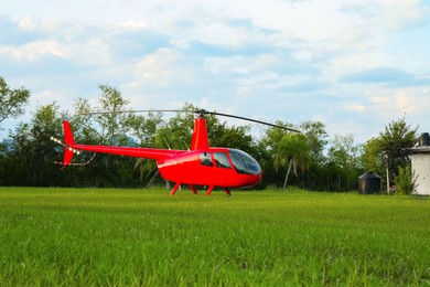 Photo of Modern red helicopter on green grass outdoors