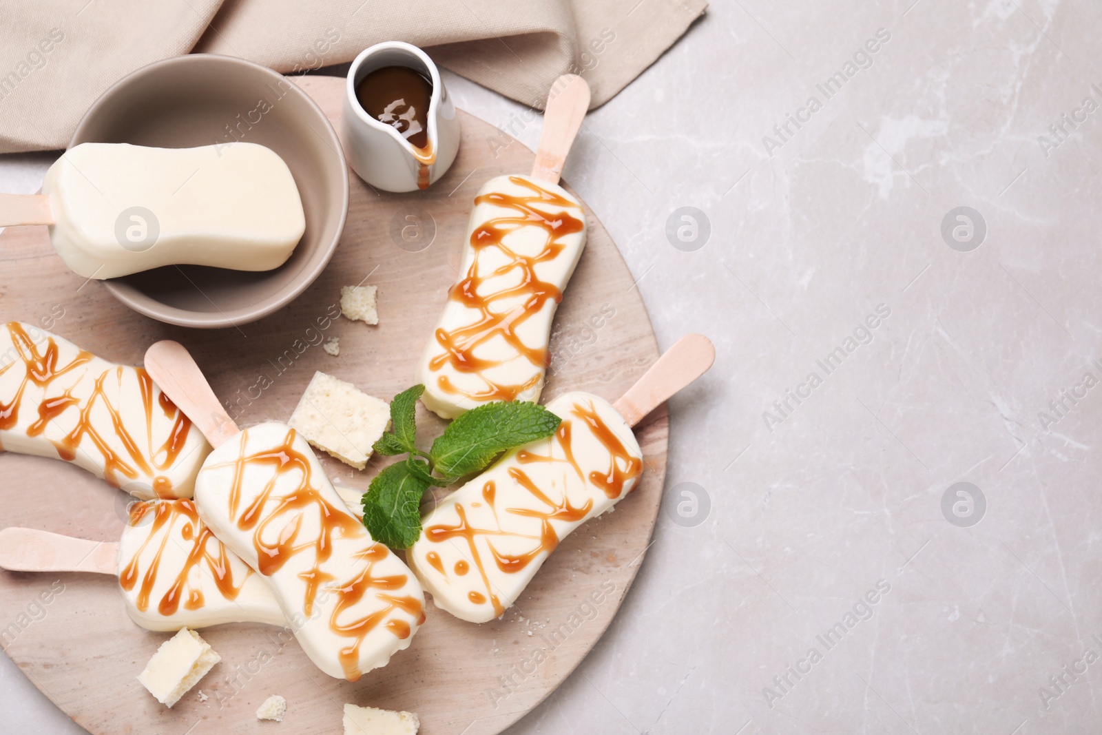 Photo of Delicious glazed ice cream bars, chocolate and mint on light grey marble table, flat lay. Space for text