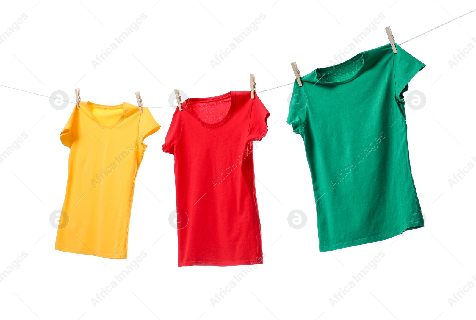 Photo of Different bright t-shirts drying on washing line against white background