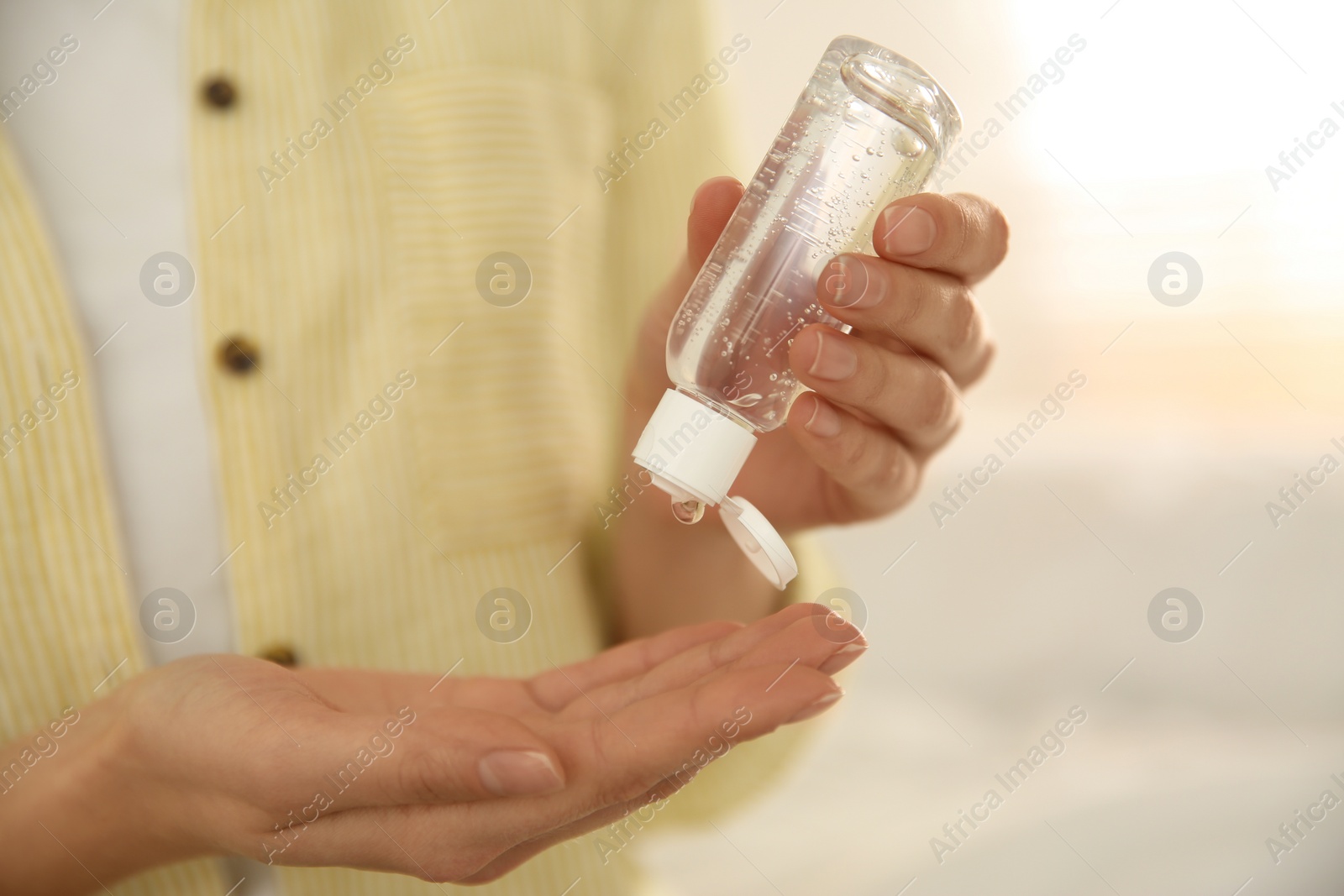 Photo of Woman applying antiseptic gel on blurred background, closeup