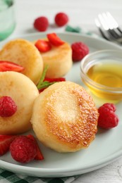 Photo of Delicious cottage cheese pancakes with fresh berries and honey on table, closeup