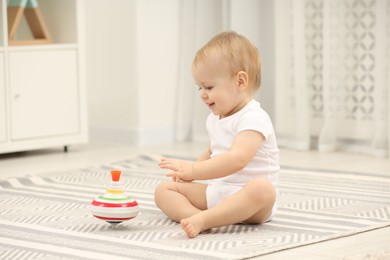 Photo of Children toys. Cute little boy and spinning top on rug at home