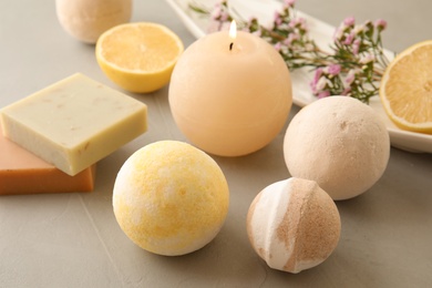 Photo of Bath bombs, soap bars and scented candle on grey table