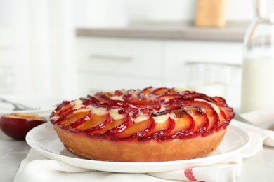 Photo of Delicious cake with plums on light table, closeup