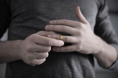 Image of Man taking off wedding ring, closeup. Cheating and breakup