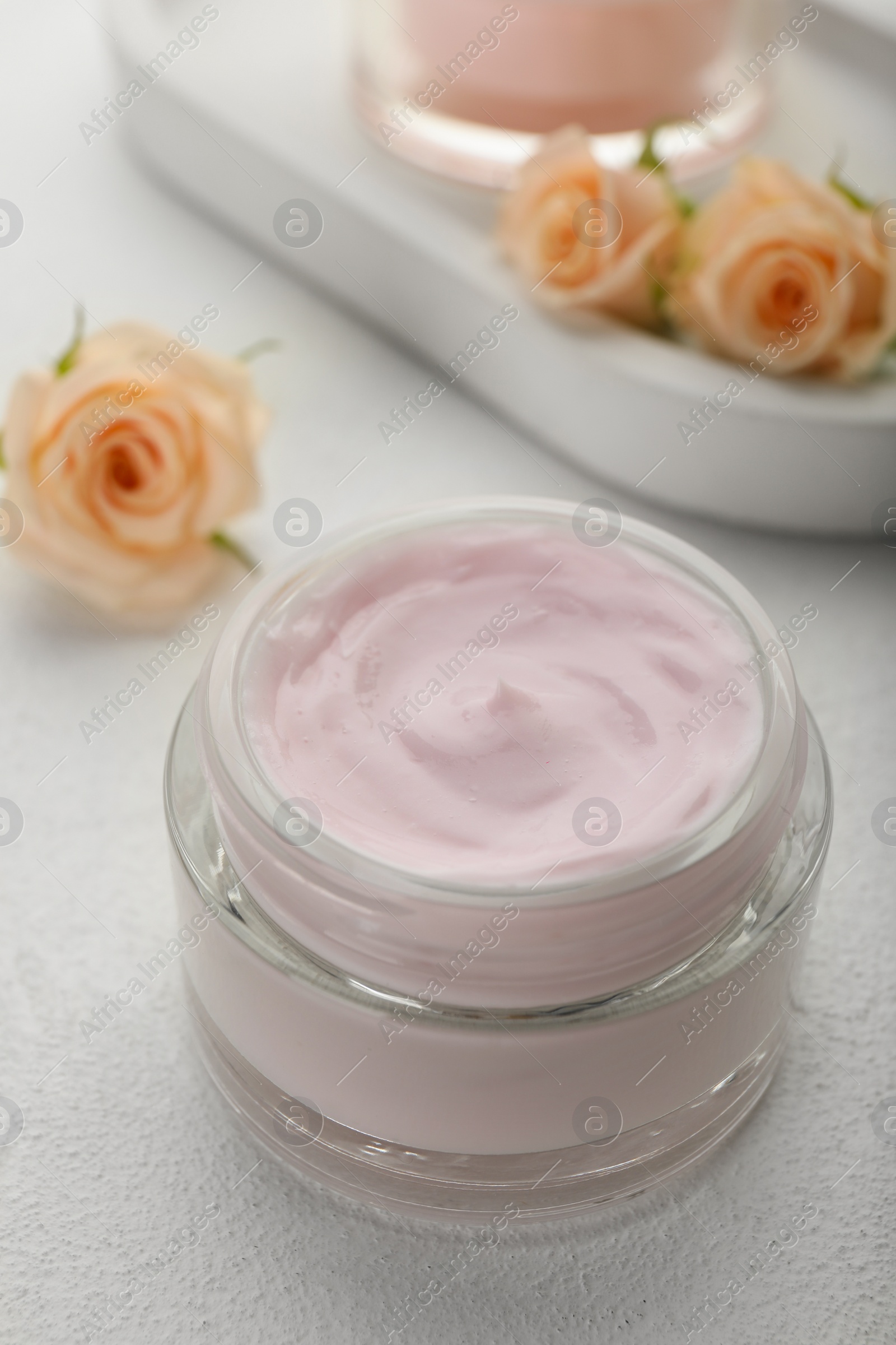 Photo of Jar of organic cream and roses on white table