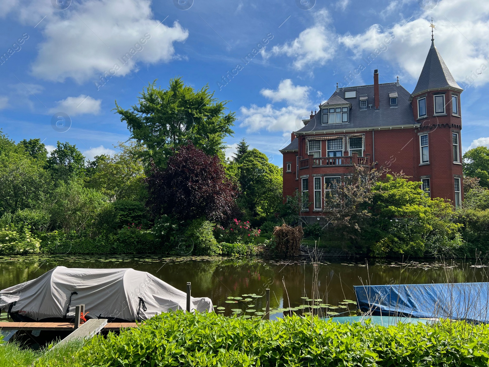 Photo of Beautiful view of house near river with moored boats on sunny day