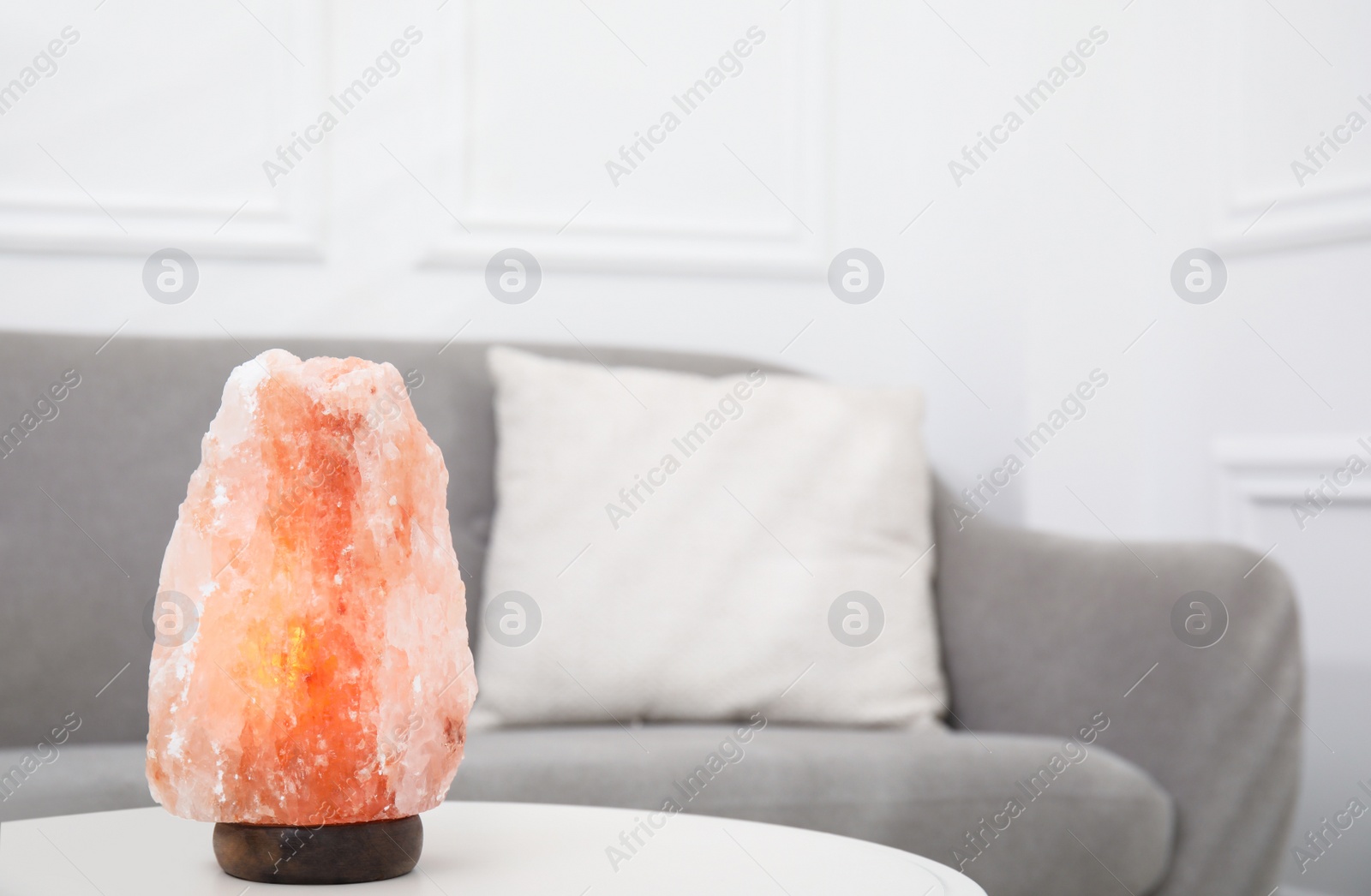 Photo of Himalayan salt lamp on white table in room. Space for text