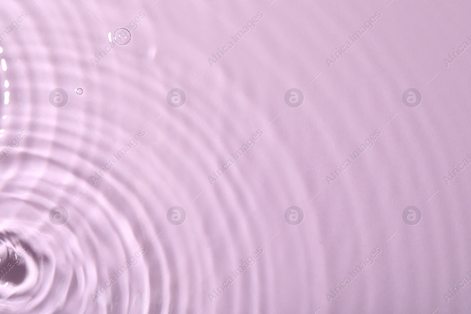 Photo of Closeup view of water with rippled surface on violet background