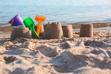 Photo of Little sand figures and plastic toys on beach near sea