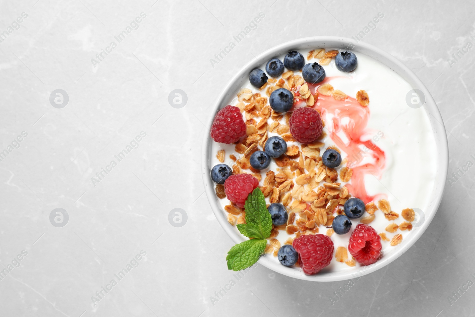 Photo of Healthy homemade granola with yogurt and berries on light grey table, top view. Space for text