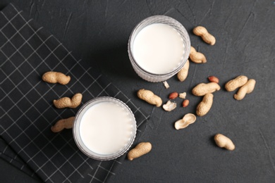 Glasses with peanut milk and nuts on grey background