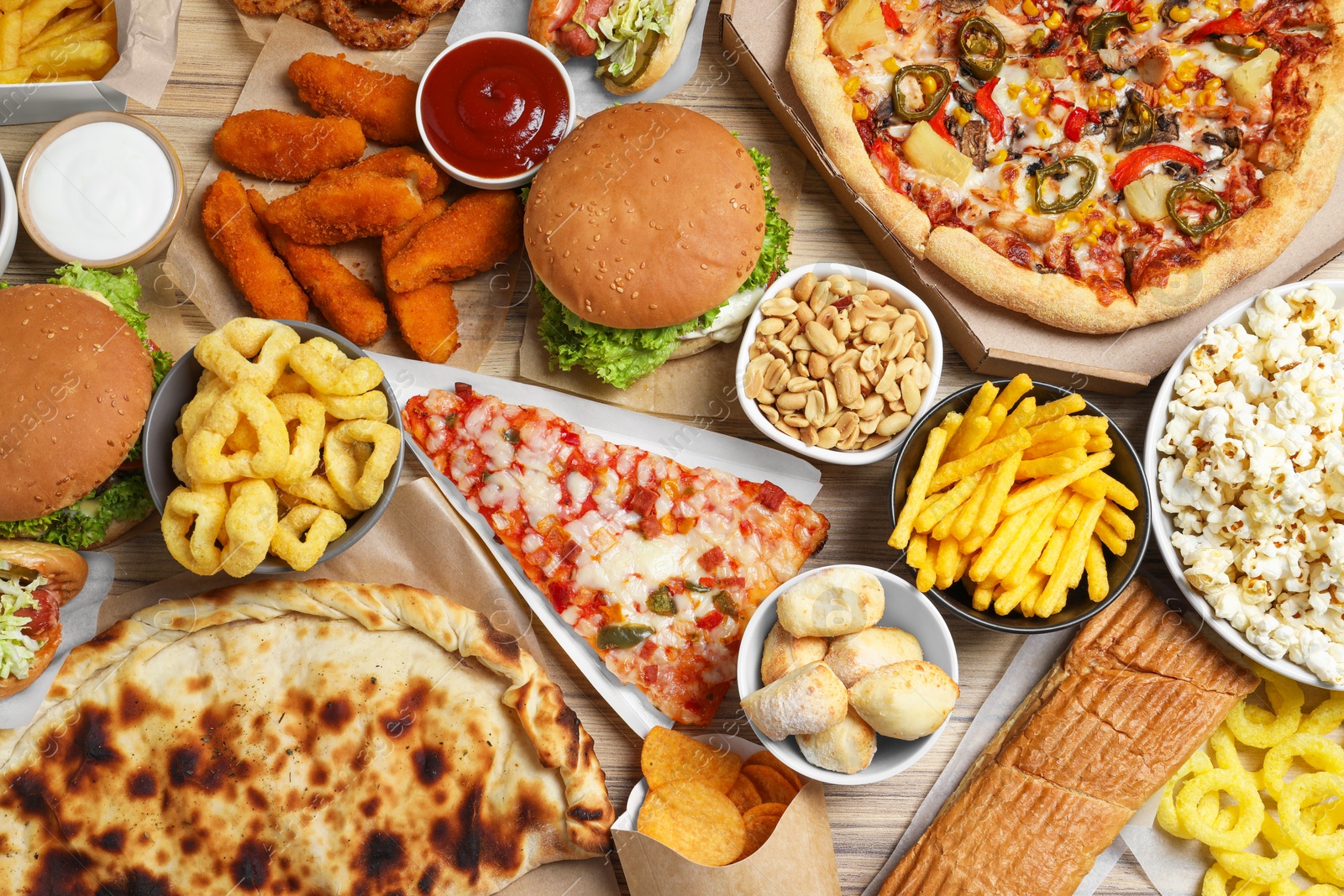 Photo of French fries, pizza and other fast food on wooden table, flat lay