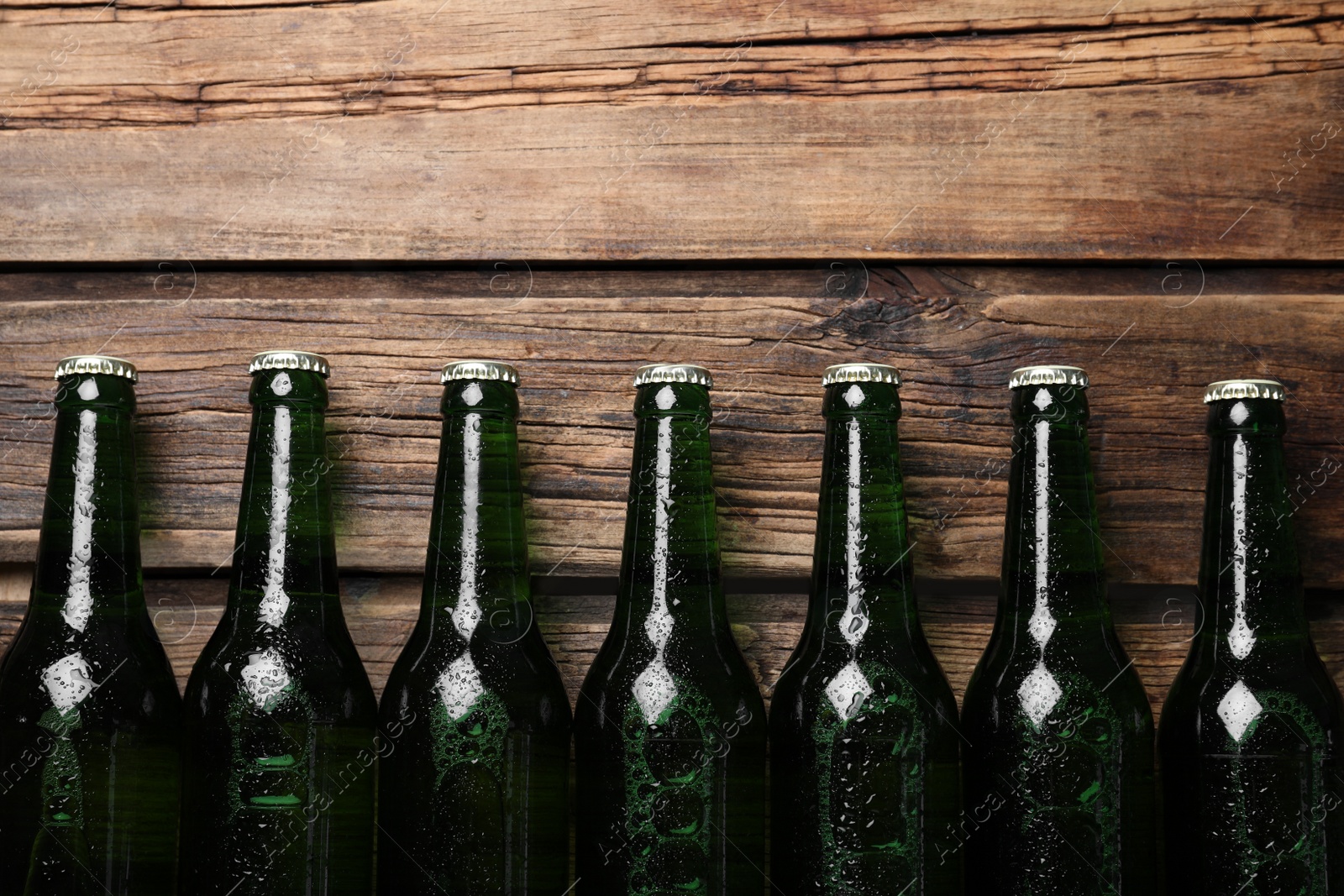 Photo of Bottles of beer on wooden table, flat lay. Space for text