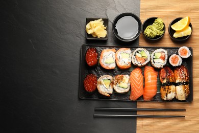 Photo of Set of delicious sushi rolls on black table, flat lay. Space for text