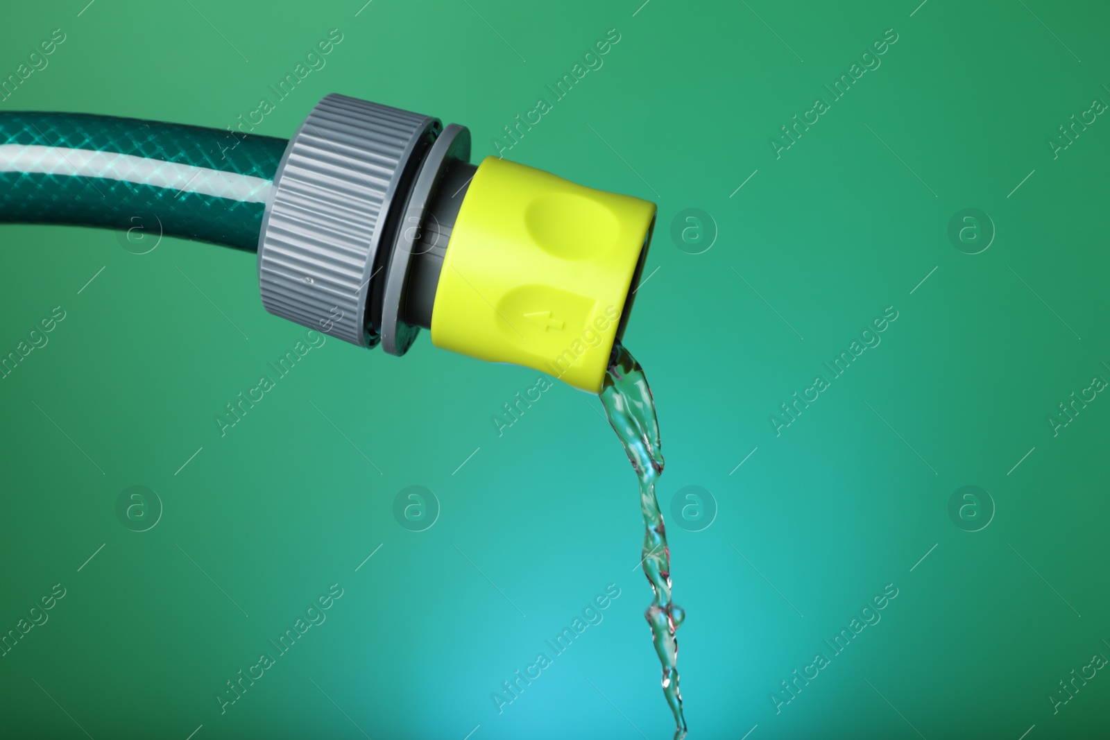 Photo of Water dripping from hose on green background, closeup. Space for text