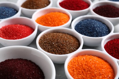 Bowls of different food coloring on light grey table, closeup