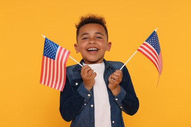 4th of July - Independence Day of USA. Happy boy with American flags on yellow background
