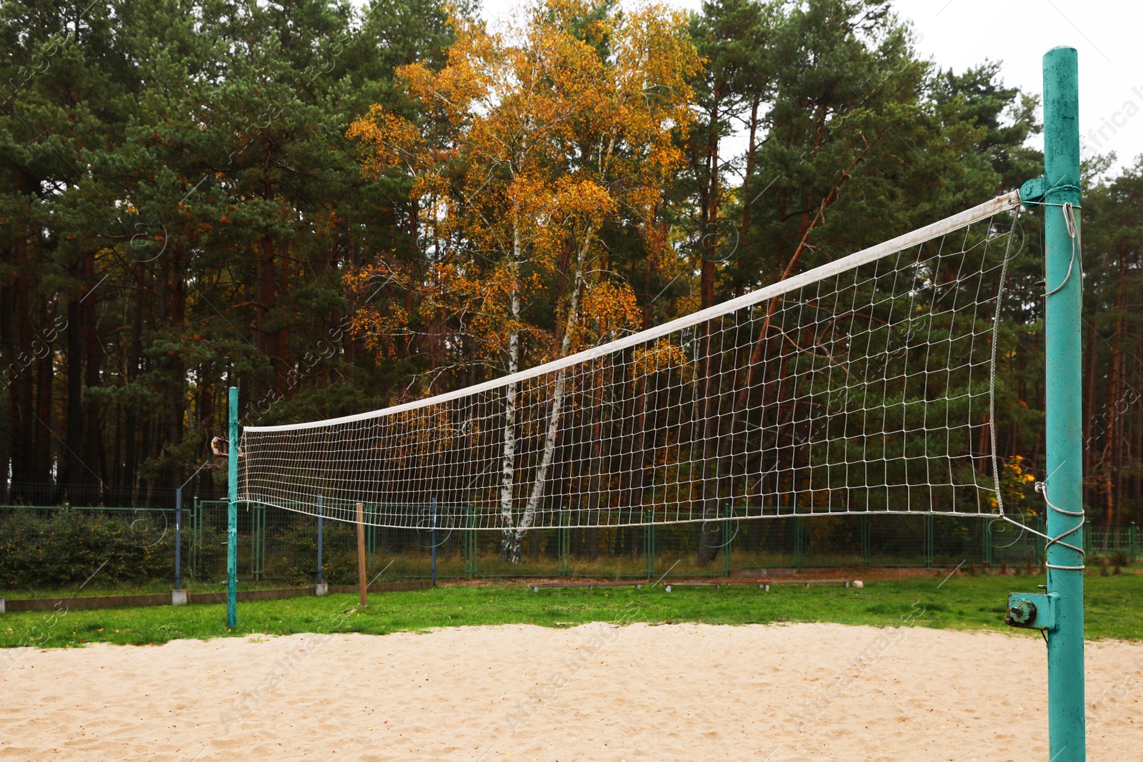 Photo of Sand volleyball court with net near trees