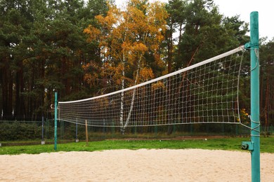 Sand volleyball court with net near trees