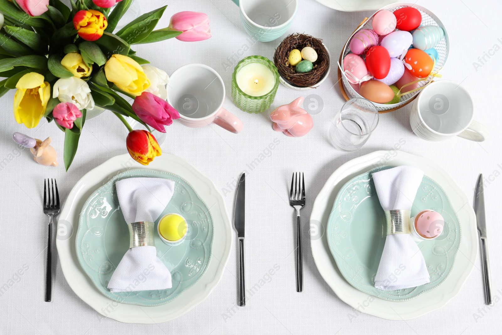 Photo of Easter celebration. Festive table setting with beautiful flowers and painted eggs, flat lay