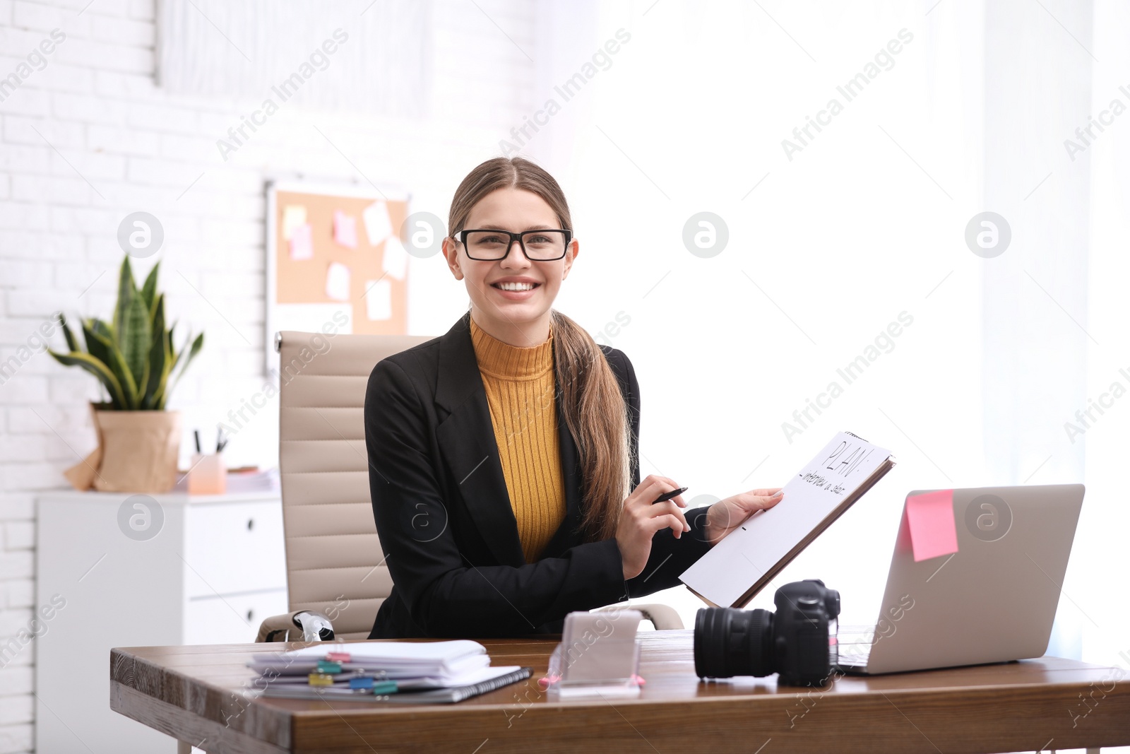 Photo of Young journalist working at table in office