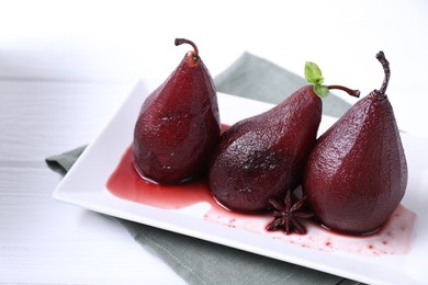 Photo of Tasty red wine poached pears with mint and anise on white wooden table, closeup