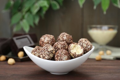 Photo of Bowl of delicious sweet chocolate candies on wooden table