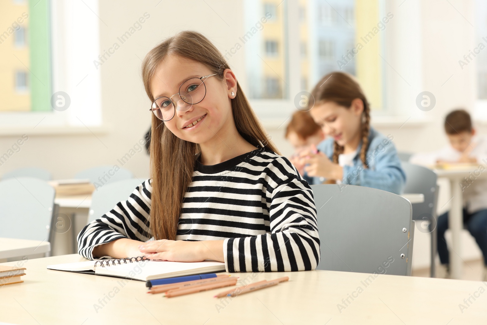 Photo of Portrait of smiling little girl studying in classroom at school