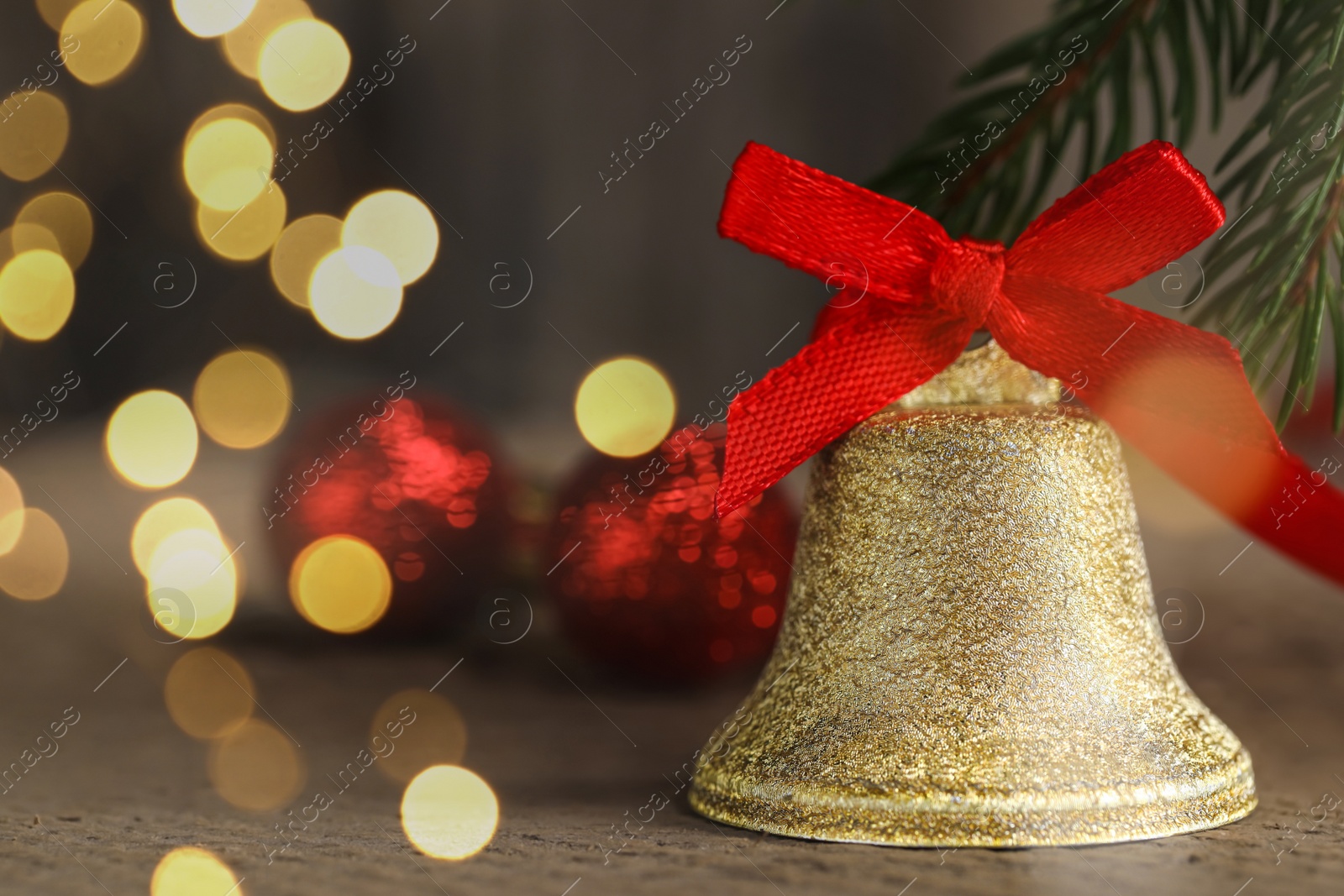 Photo of Bell with red bow on wooden table, closeup and space for text. Christmas decor