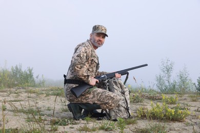 Man wearing camouflage with hunting rifle and backpack outdoors