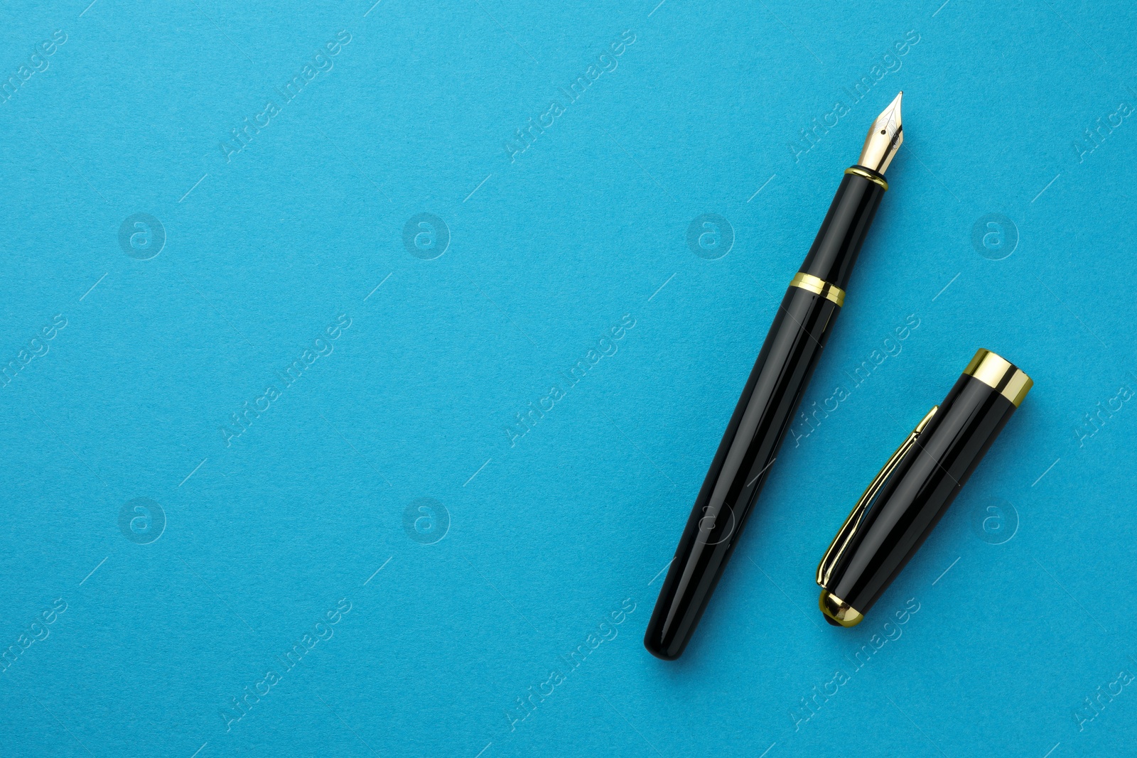 Photo of Stylish fountain pen with cap on light blue background, flat lay. Space for text