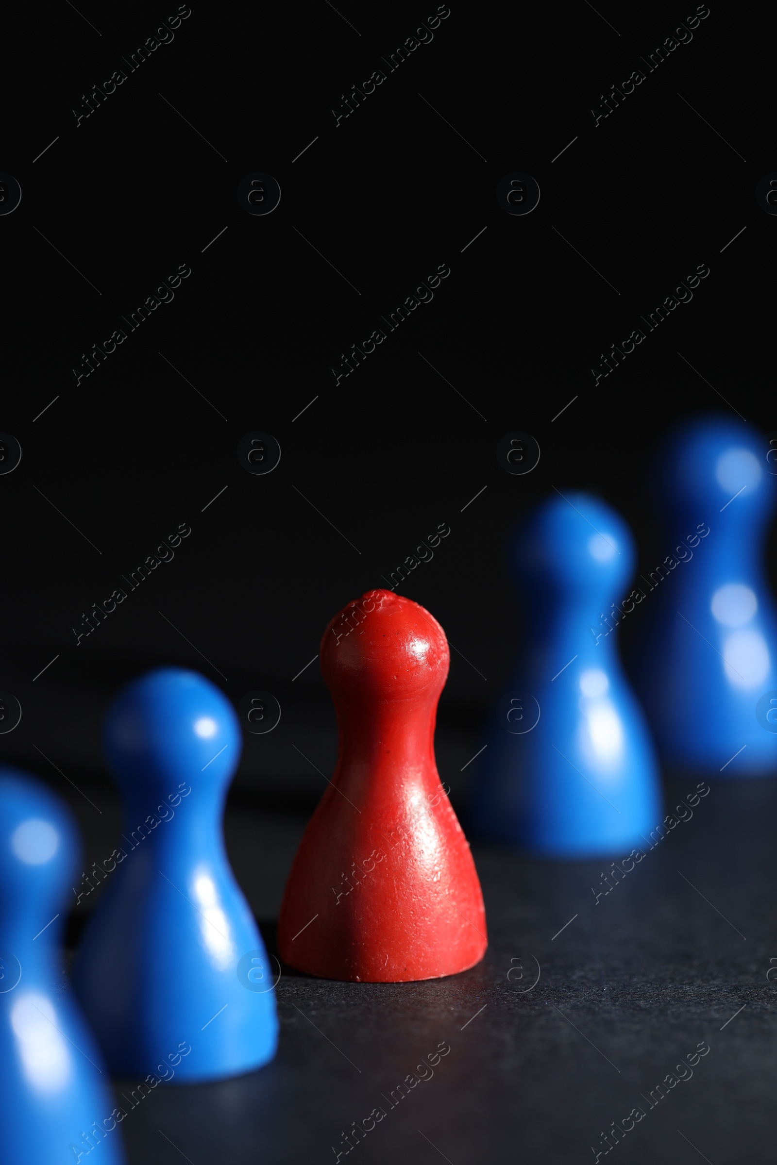 Photo of Choice concept. Red pawn among blue ones on black table, closeup. Space for text