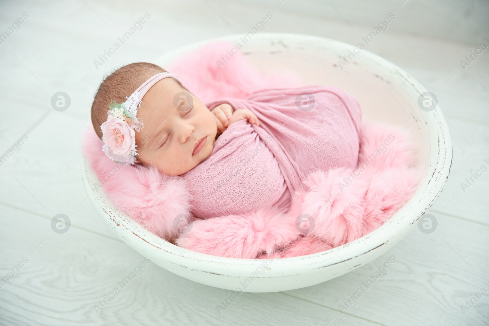 Photo of Adorable newborn girl lying in baby nest on light background