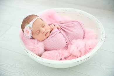 Photo of Adorable newborn girl lying in baby nest on light background