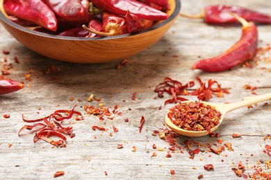 Photo of Spoon with chili pepper flakes on table