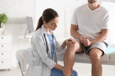 Photo of Female orthopedist examining patient's leg in clinic