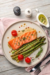 Tasty grilled salmon with tomatoes, asparagus and spices served on wooden table, flat lay