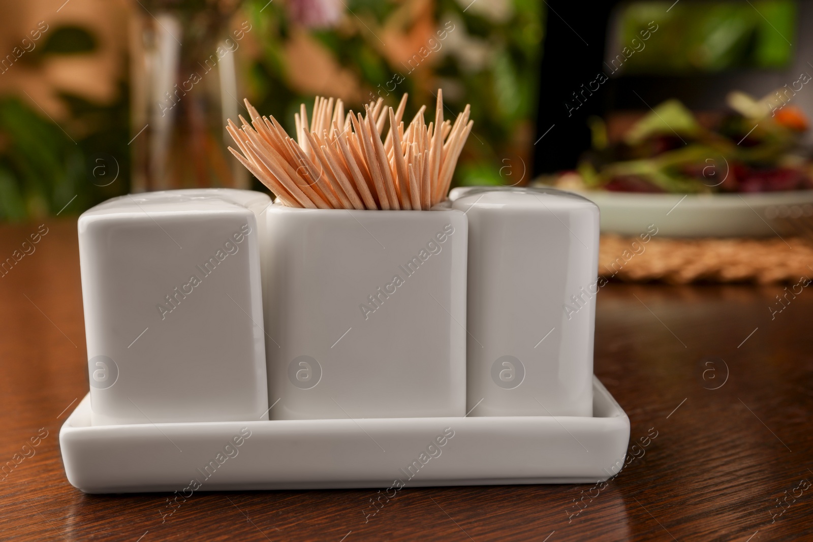 Photo of Holder with salt, pepper and toothpicks on wooden table, closeup