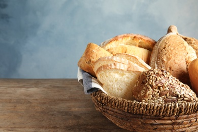 Photo of Basket with fresh bread on table against color background. Space for text