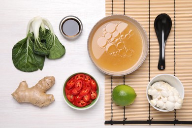 Cooking delicious ramen soup. Different ingredients and spoon on white wooden table, flat lay