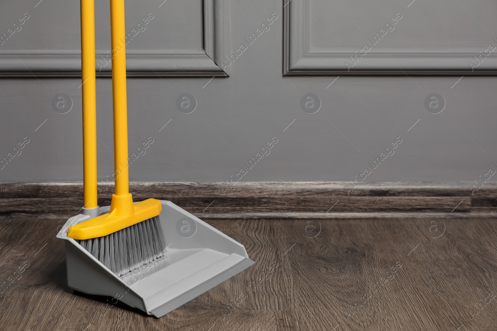 Photo of Plastic broom with dustpan near grey wall indoors. space for text