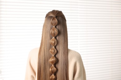 Woman with braided hair indoors, back view