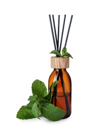 Photo of Aromatic reed air freshener and mint on white background