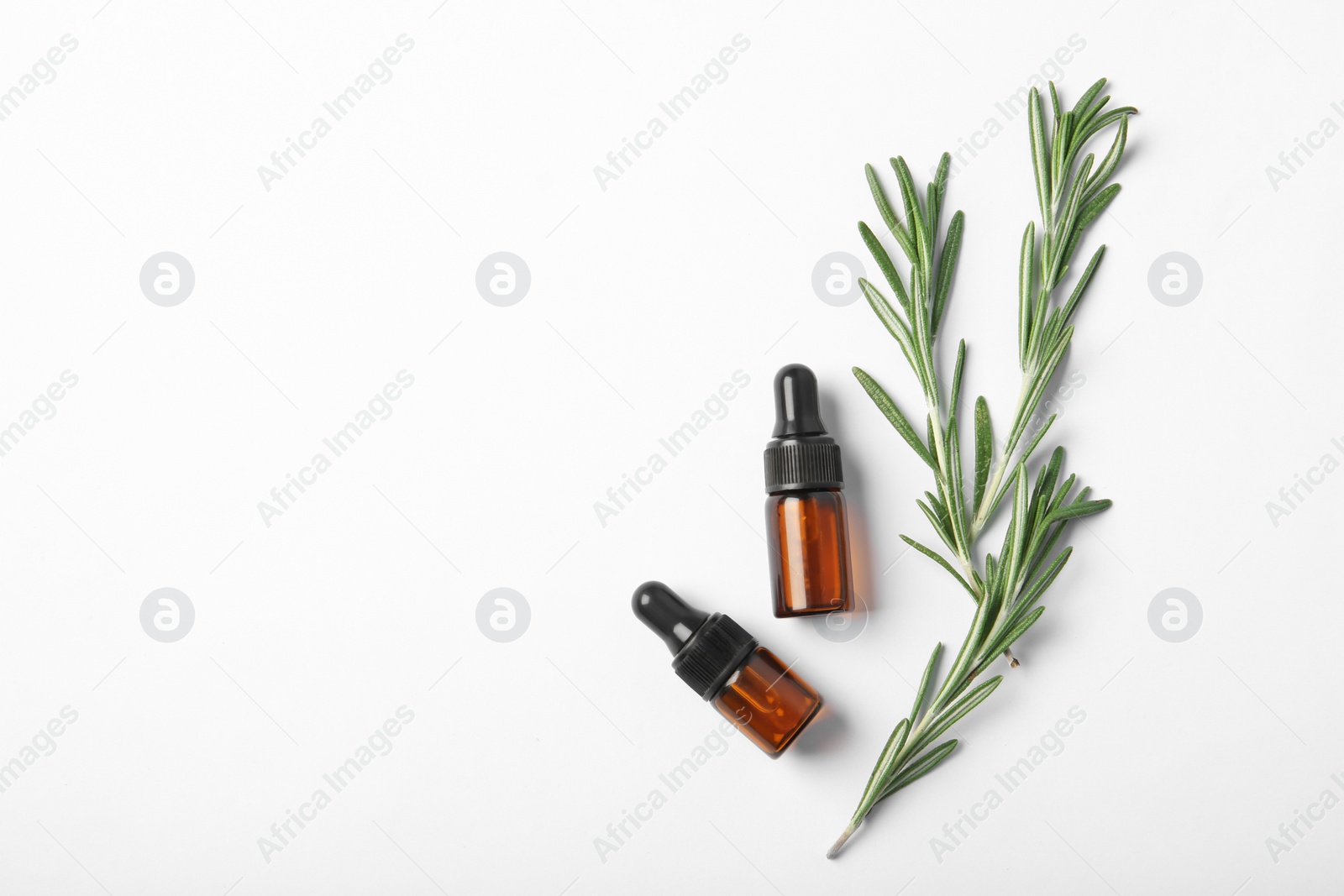 Photo of Bottles of rosemary oil and fresh twigs on white background, top view