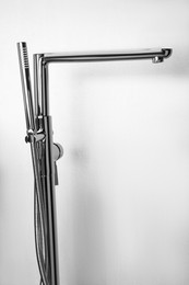 Photo of Modern bathtub faucet with hand shower on light grey background