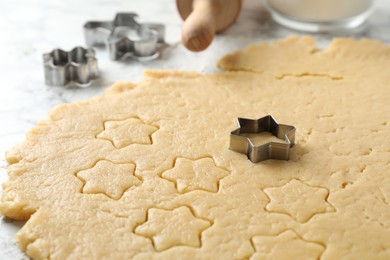 Making shortcrust pastry. Raw dough and cookie cutters on table, closeup