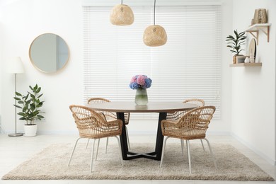 Photo of Table, chairs and vase of hydrangea flowers in dining room. Stylish interior