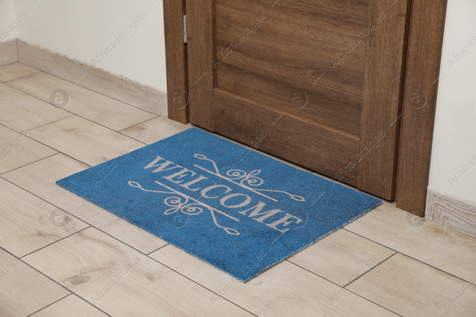 Photo of Beautiful blue doormat with word Welcome on floor near entrance