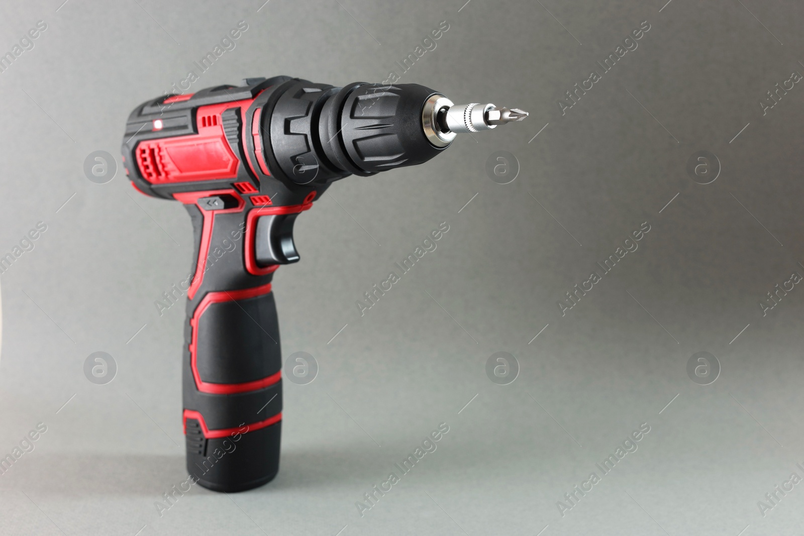 Photo of Modern cordless electric screwdriver on grey background. Space for text